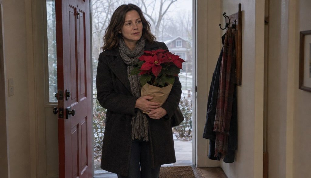 a woman in a winter coat carrying a paper-wrapped poinsettia through her front door